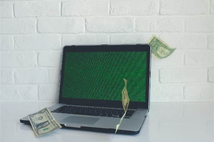 Hacked laptop with american dollar bills falling